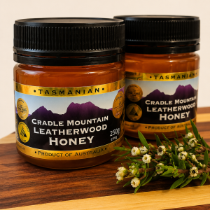 Cradle Mountain Leatherwood Honey on a wooden serving board with Leatherwood blossom, showcasing premium 100% Tasmanian honey.