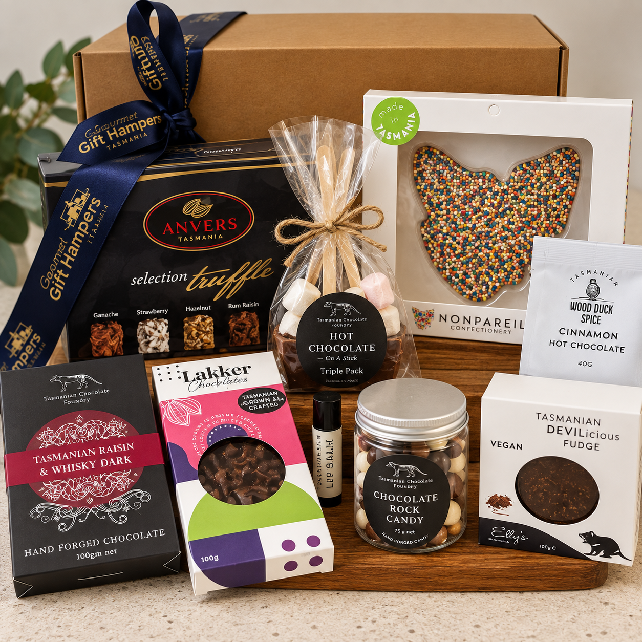 Tasmanian Chocolate Indulgence Hamper contents including Anvers Selection Truffles, Nonpareil chocolate freckle, Tasmanian Chocolate Foundry Raisin & Whisky Dark, Lakker Chocolates, hot chocolate on a stick, Wood Duck Spice hot chocolate, Elly's vegan fudge, and chocolate rock candy